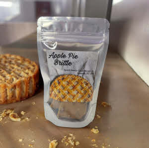 bag of apple pie brittle on a counter with an apple pie